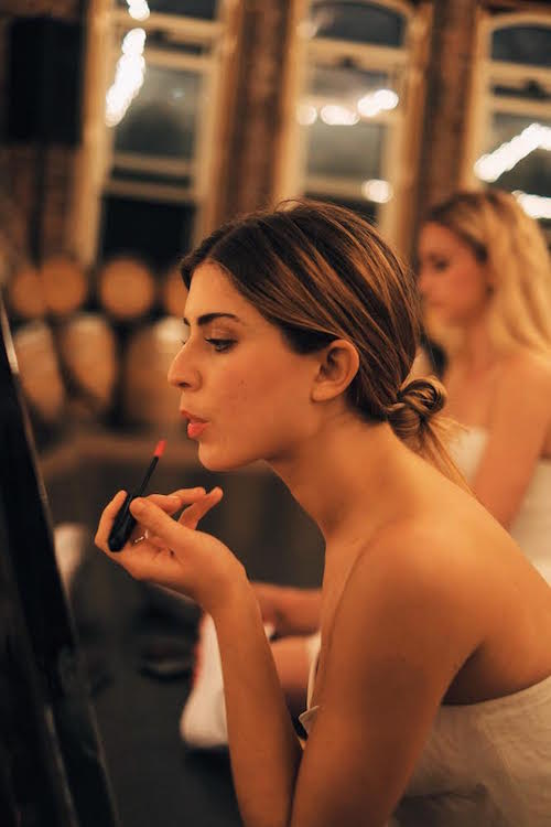 A young debutaunte applies lipstick in the mirror